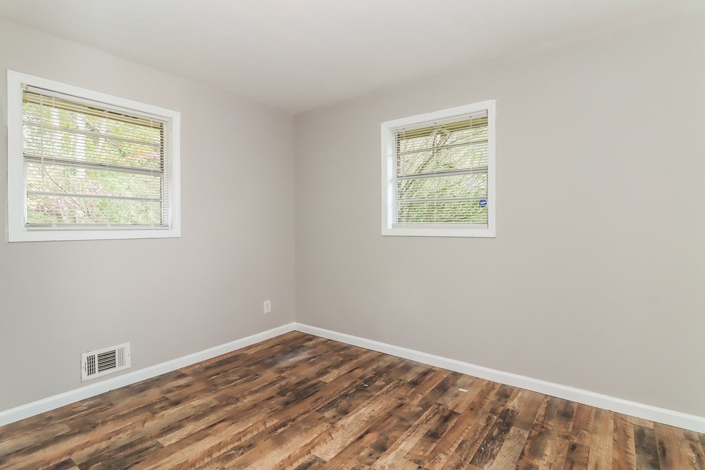 A room with wooden floors and two windows.