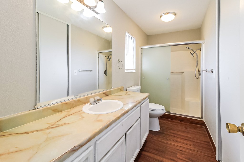 A bathroom with a marble countertop and a walk-in shower.