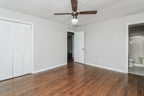 A room with a ceiling fan and wooden floors.