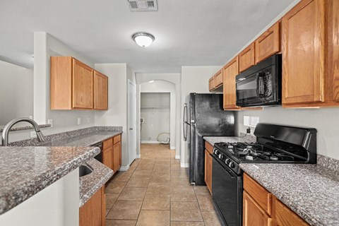 A kitchen with black appliances and wooden cabinets.