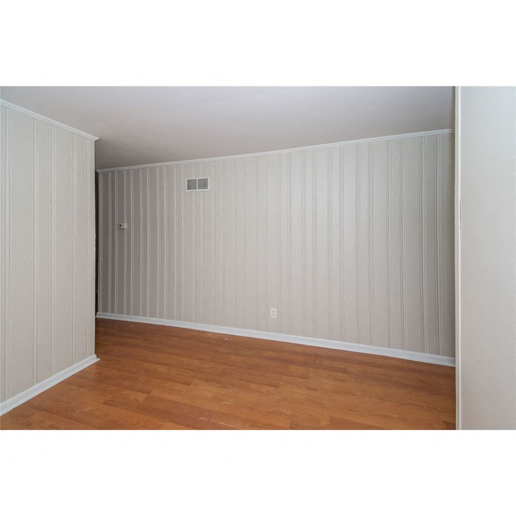 an empty room with a wood floor and white walls