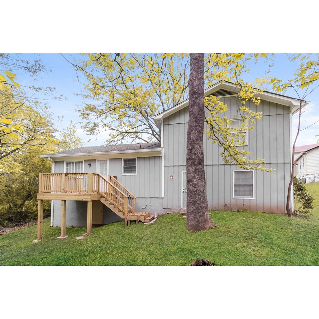 a view of the back of a house with a deck and a tree