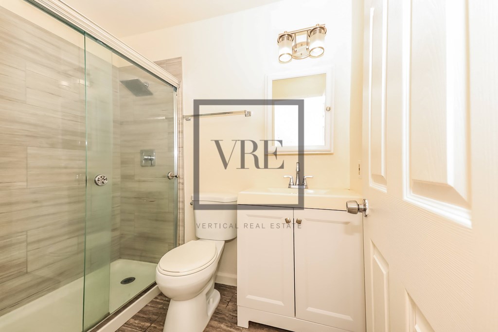 A bathroom with a glass shower door and a white toilet.
