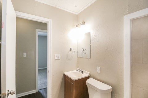 A bathroom with a toilet, sink, and mirror.