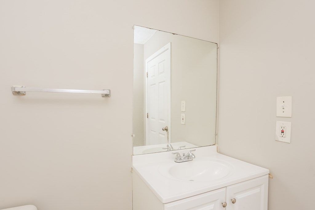 A white bathroom vanity with a mirror and a towel bar.