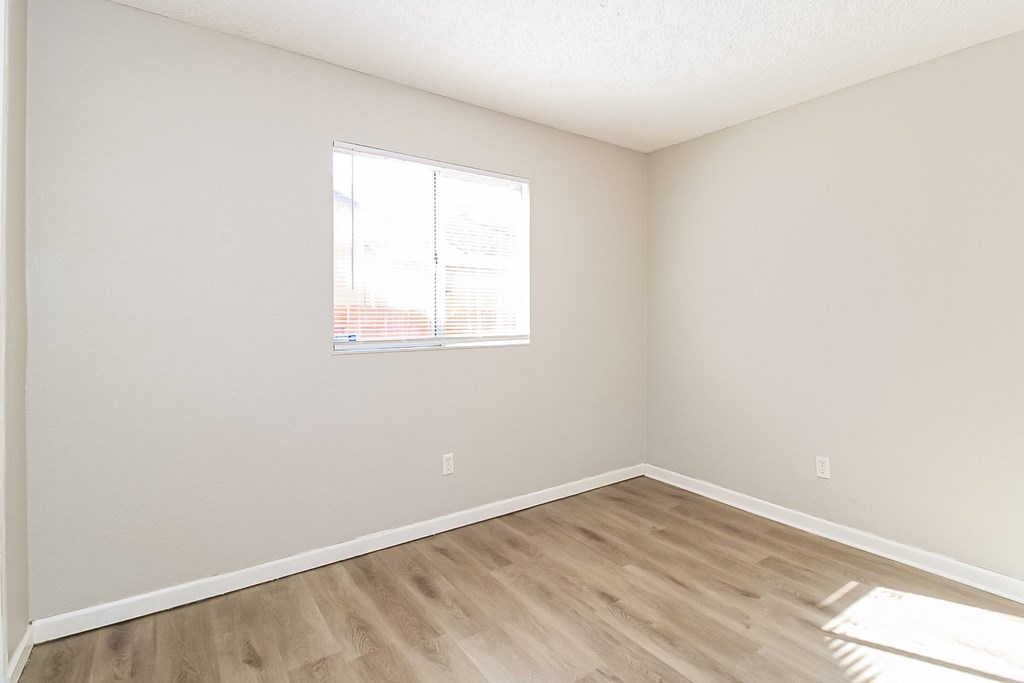 A room with a window and wooden flooring.