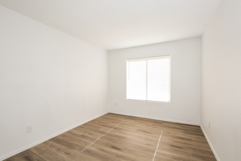 A room with a window and wooden flooring.