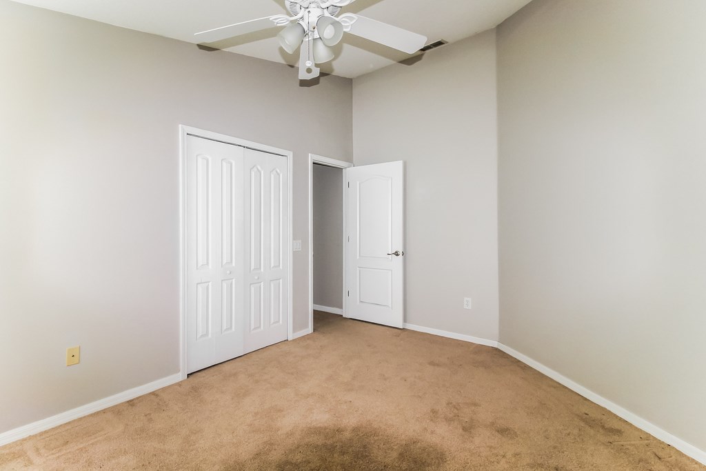 A room with a ceiling fan and two doors.