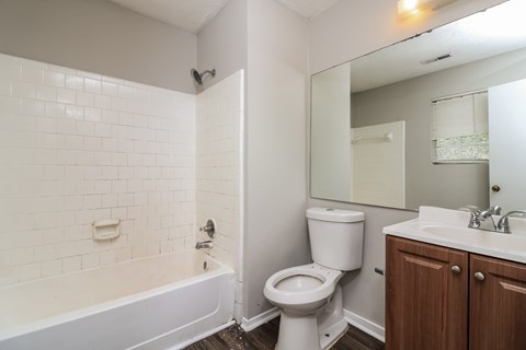 A white tiled bathroom with a toilet, sink, and bathtub.