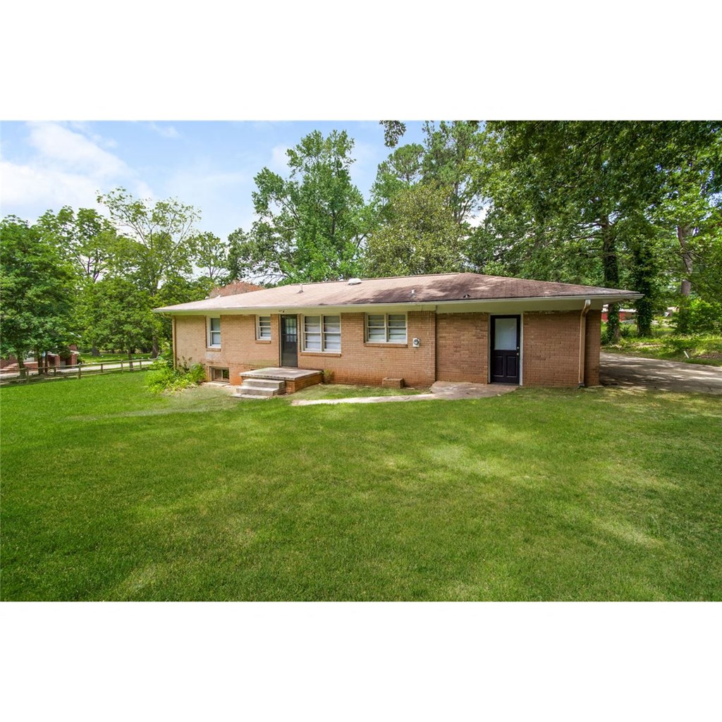 a small brick house in the middle of a grassy yard