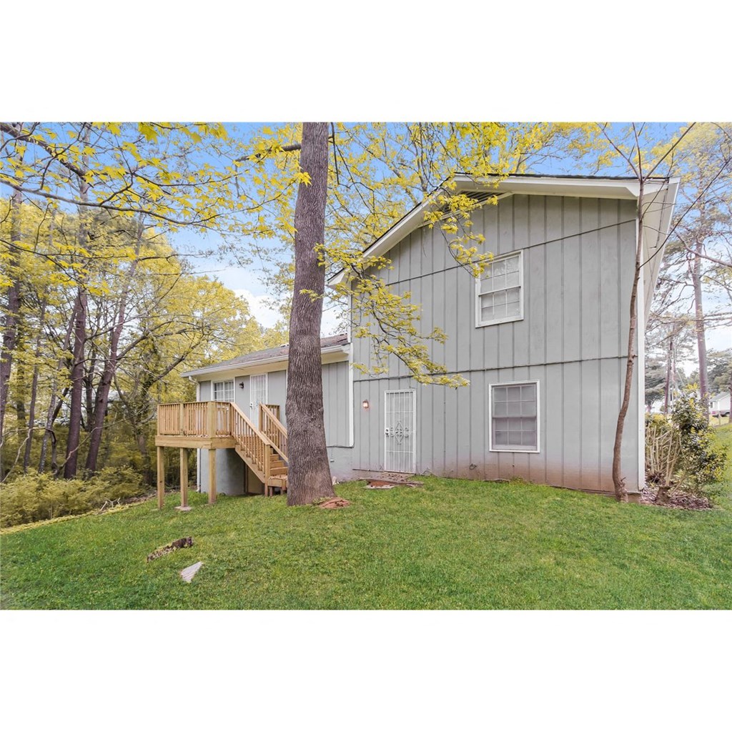 the front of the house with the deck and the tree