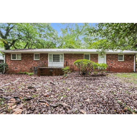 a brick house with a yard covered in fallen leaves