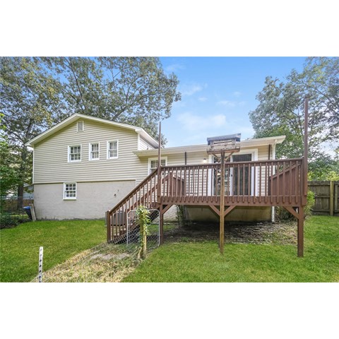 A house with a deck and a tree in front.