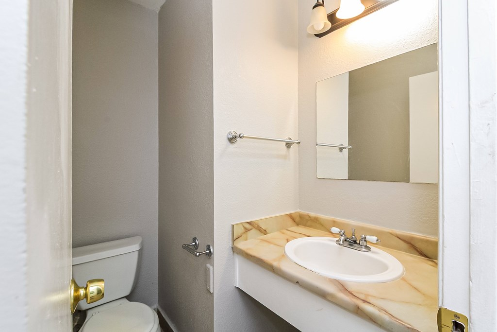A bathroom with a marble countertop and a toilet.