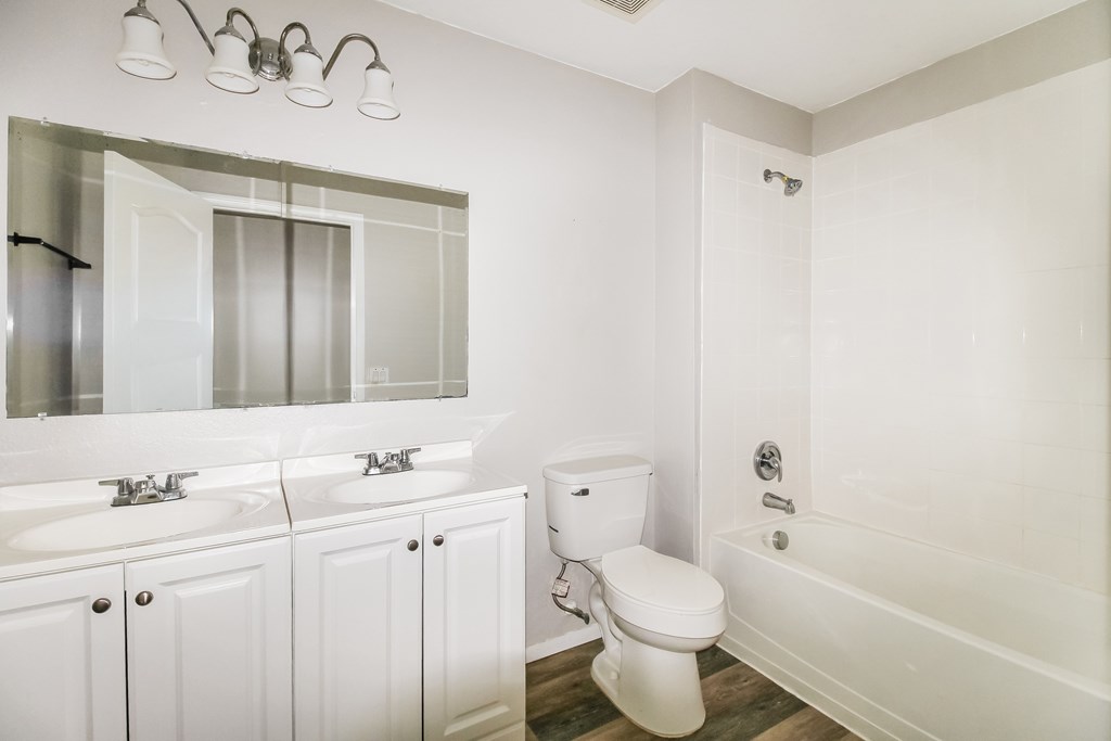 A white bathroom with a toilet, sink, and mirror.