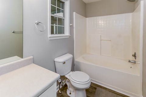 A white toilet sits next to a bathtub in a bathroom.