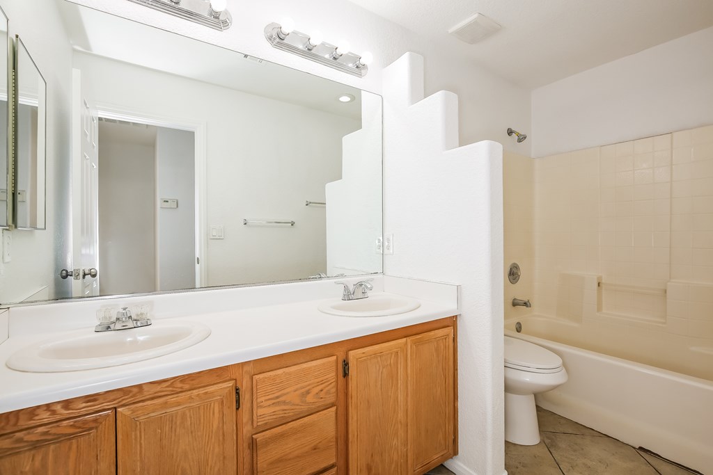 A white bathroom with a double sink and a bathtub.