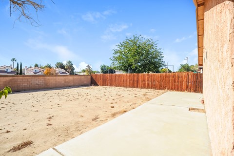 A backyard with a wooden fence and a concrete path.