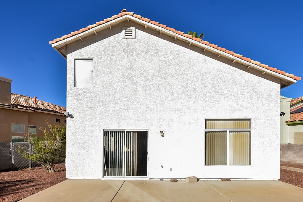 A white house with a brown roof and a black gate.