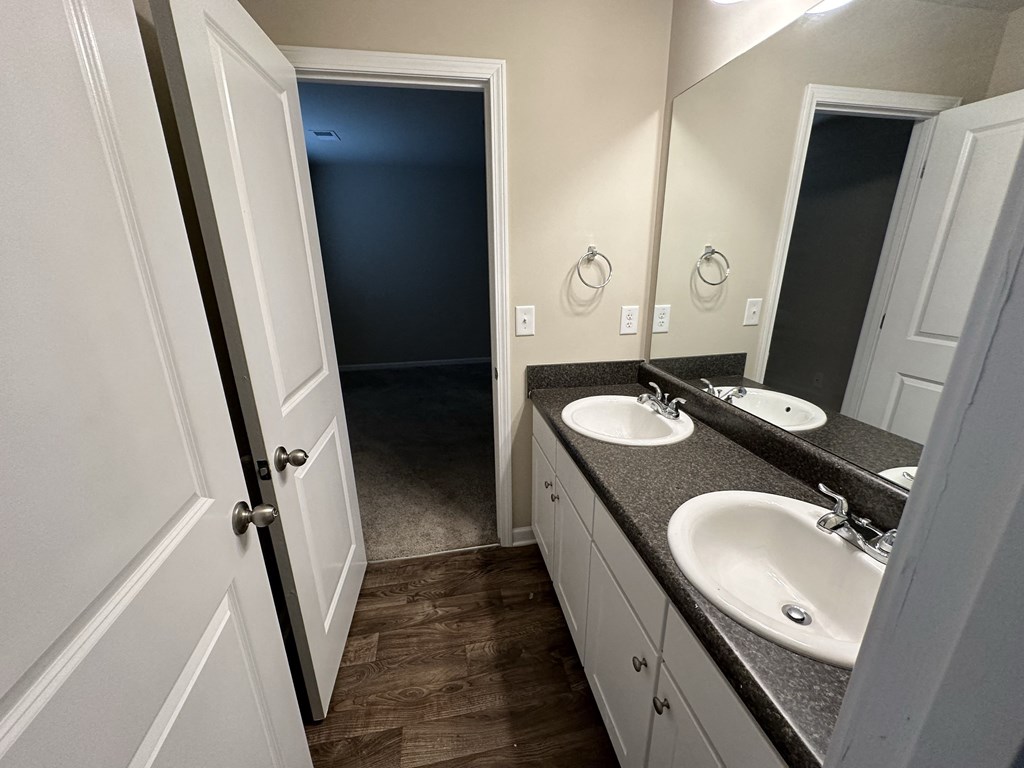 an empty bathroom with two sinks and a door to a closet
