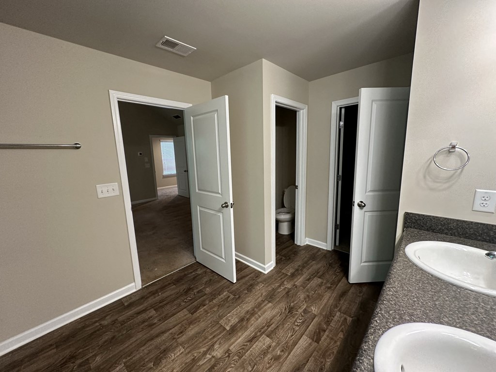 a bathroom with a sink and a mirror and a hallway with three doors