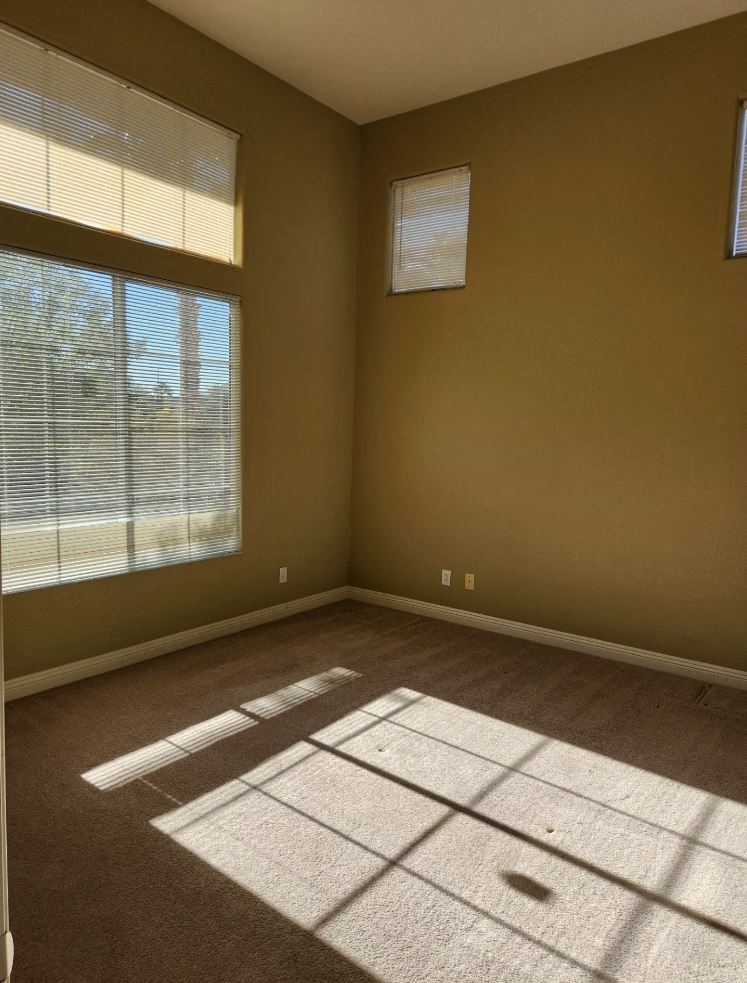 an empty room with two windows and a carpet