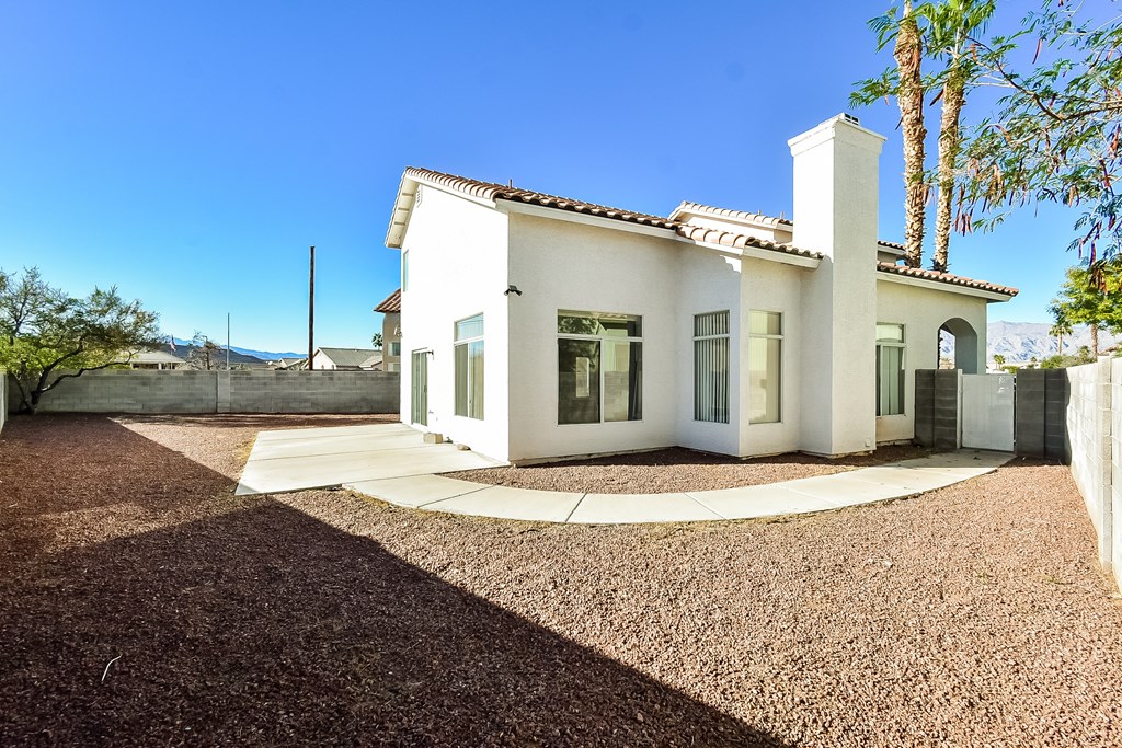 A white house with a brown gravel driveway.