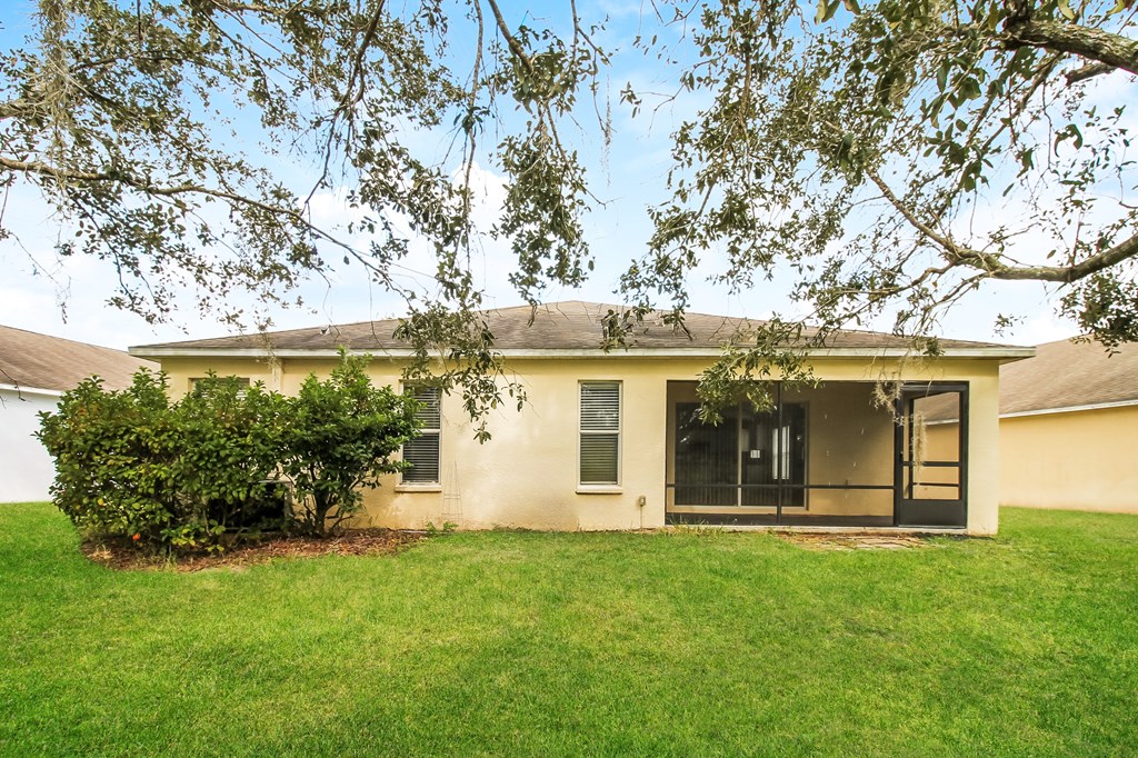 A house with a green lawn and trees in front.
