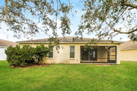 A house with a green lawn and trees in front.