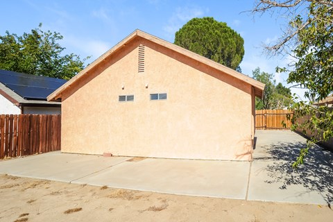 A small tan building with a brown fence in front.