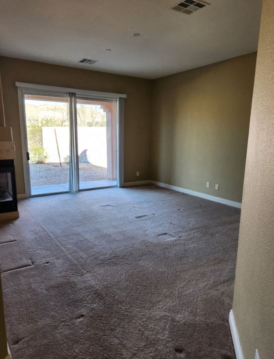 an empty living room with a fireplace and sliding glass doors