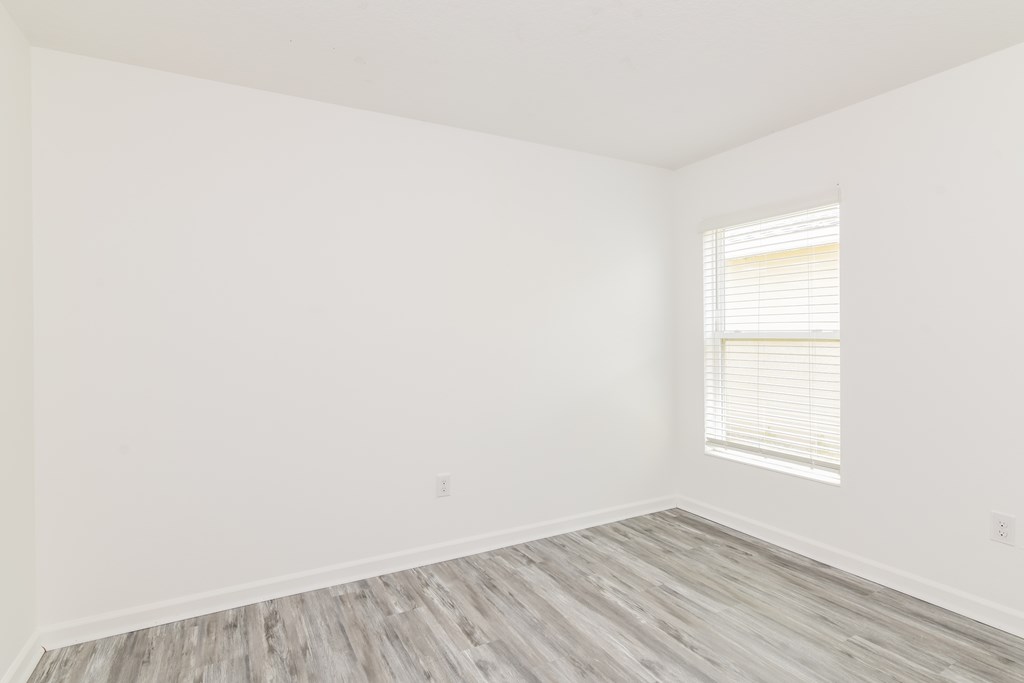 A room with a window and wooden flooring.