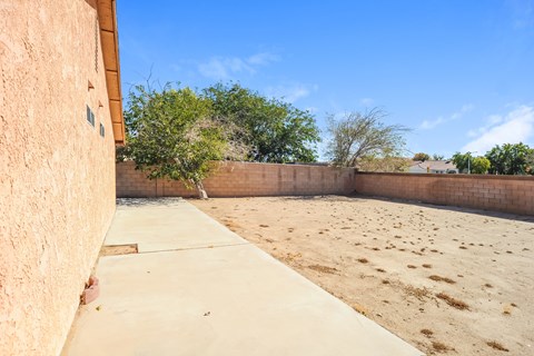 A backyard with a concrete walkway and a wall.