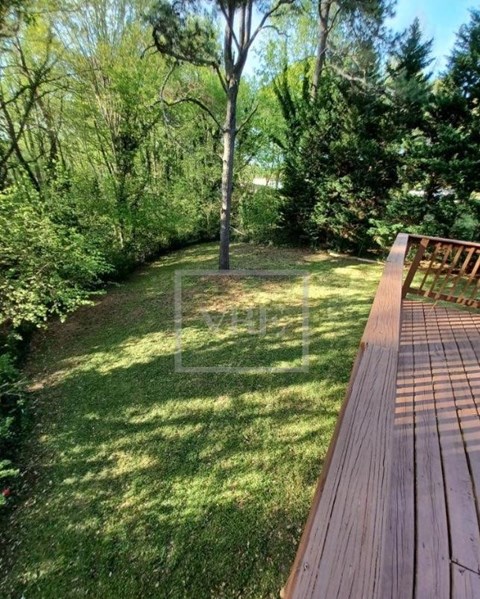 A wooden deck overlooks a grassy area with trees.