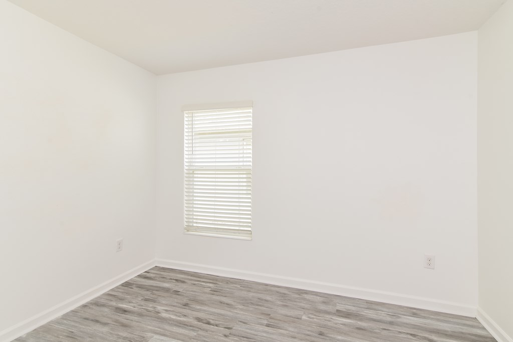 A room with a window and wooden flooring.