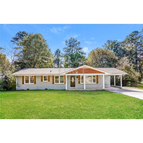 a small white house with a lawn and trees
