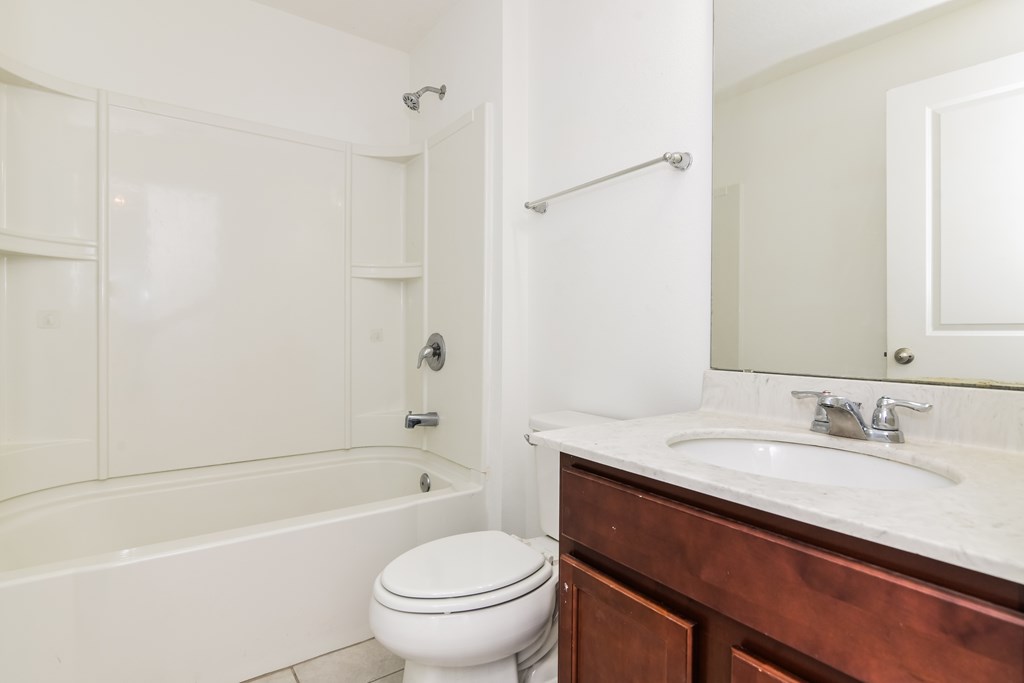 A white toilet sits next to a white bathtub in a bathroom.