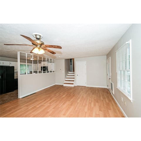 A room with a ceiling fan and wooden floors.