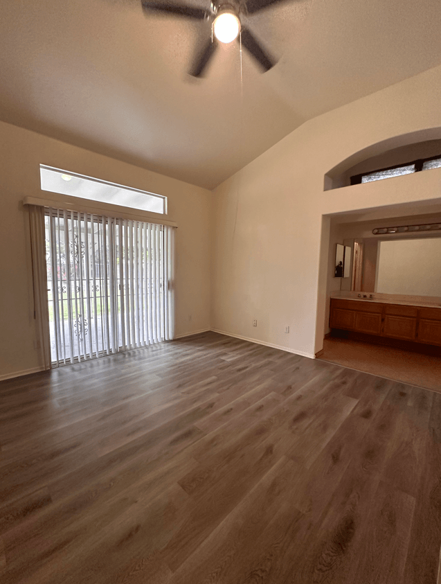 an empty living room with wood floors and a sliding glass door