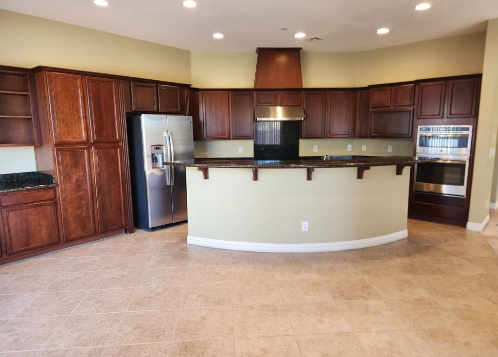 a kitchen with a center island and a stainless steel refrigerator