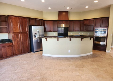 a kitchen with a center island and a stainless steel refrigerator