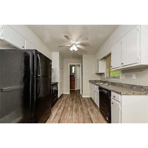 a kitchen with white cabinets and a black refrigerator