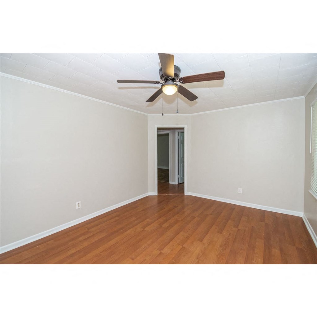 an empty living room with a ceiling fan