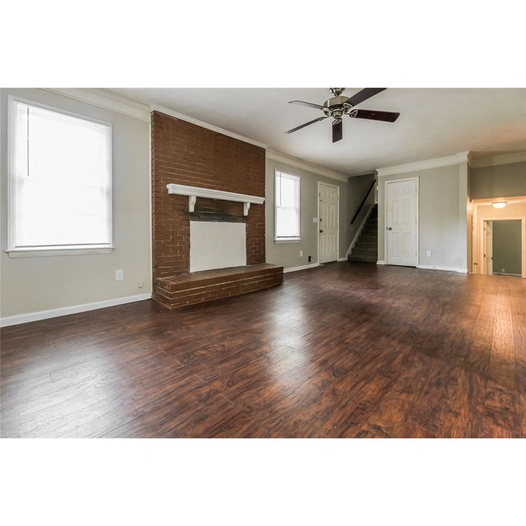 an empty living room with a fireplace and a ceiling fan