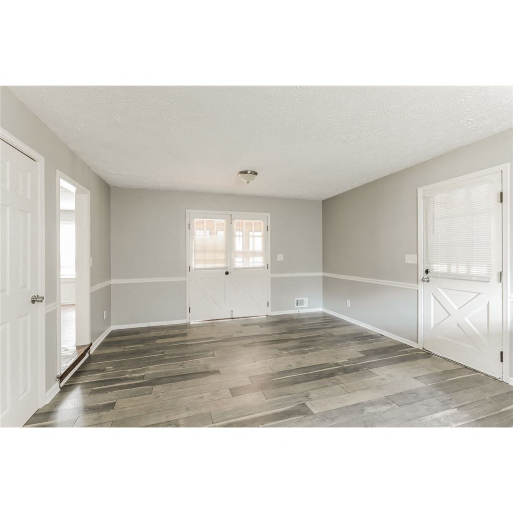a spacious living room with white doors and wood floors