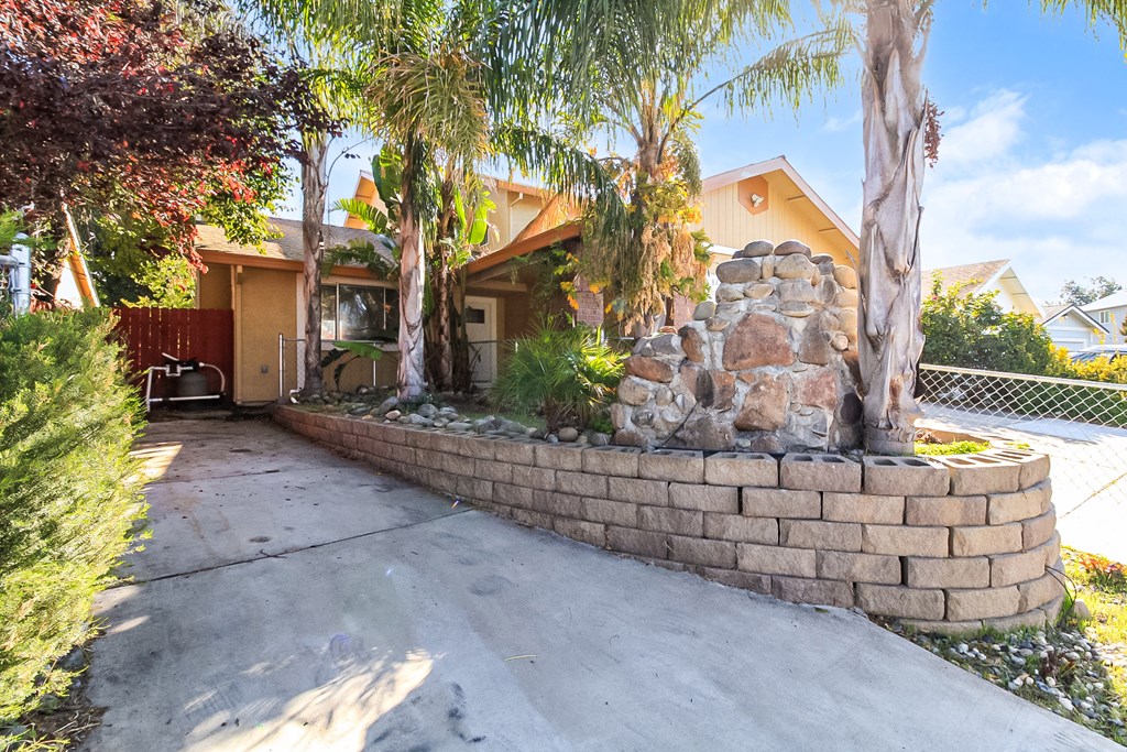 A house with a stone wall and trees in front.