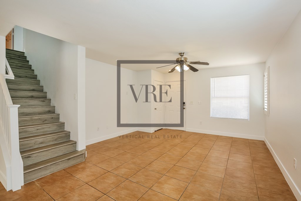 A spacious room with a staircase and a fan.