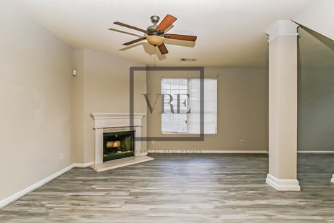 A spacious room with a fireplace and a fan.