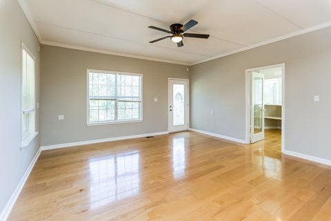 A room with a ceiling fan and wooden flooring.
