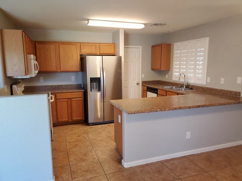 A kitchen with a white refrigerator and brown cabinets.